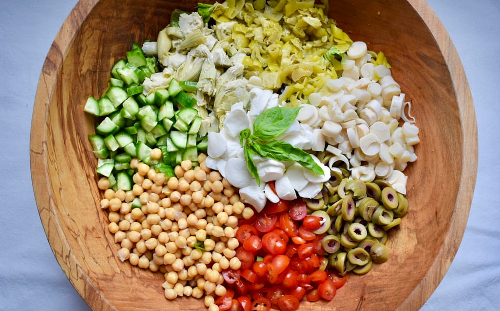 Italian chopped salad with vegetables arranged on top of chopped lettuce. 