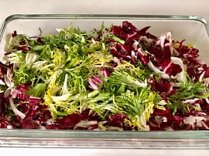 Chicory greens chopped and stored in an airtight glass container.