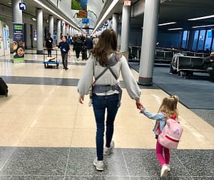 Walking through airport in sneakers with baby carrier and toddler