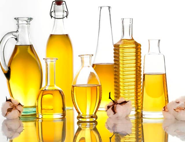 seven glass bottles of unlabeled vegetable oil