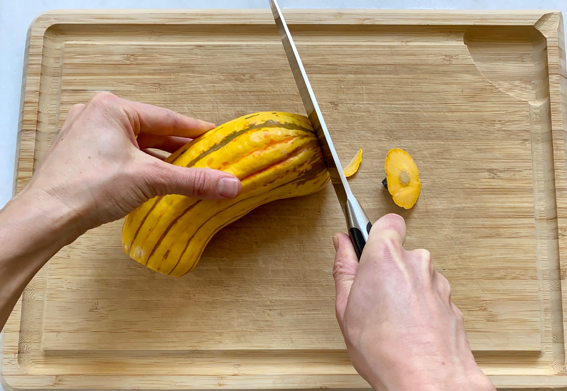 Preparing delicata squash. Begin by slicing off ends.