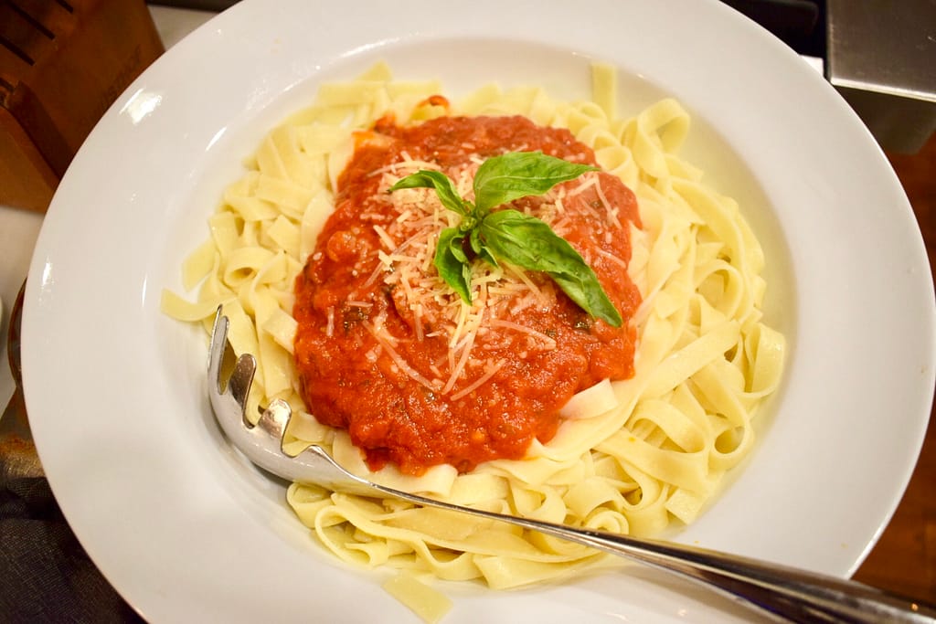 Easy homemade pasta sauce on gluten free pasta topped with basil and parmesan cheese