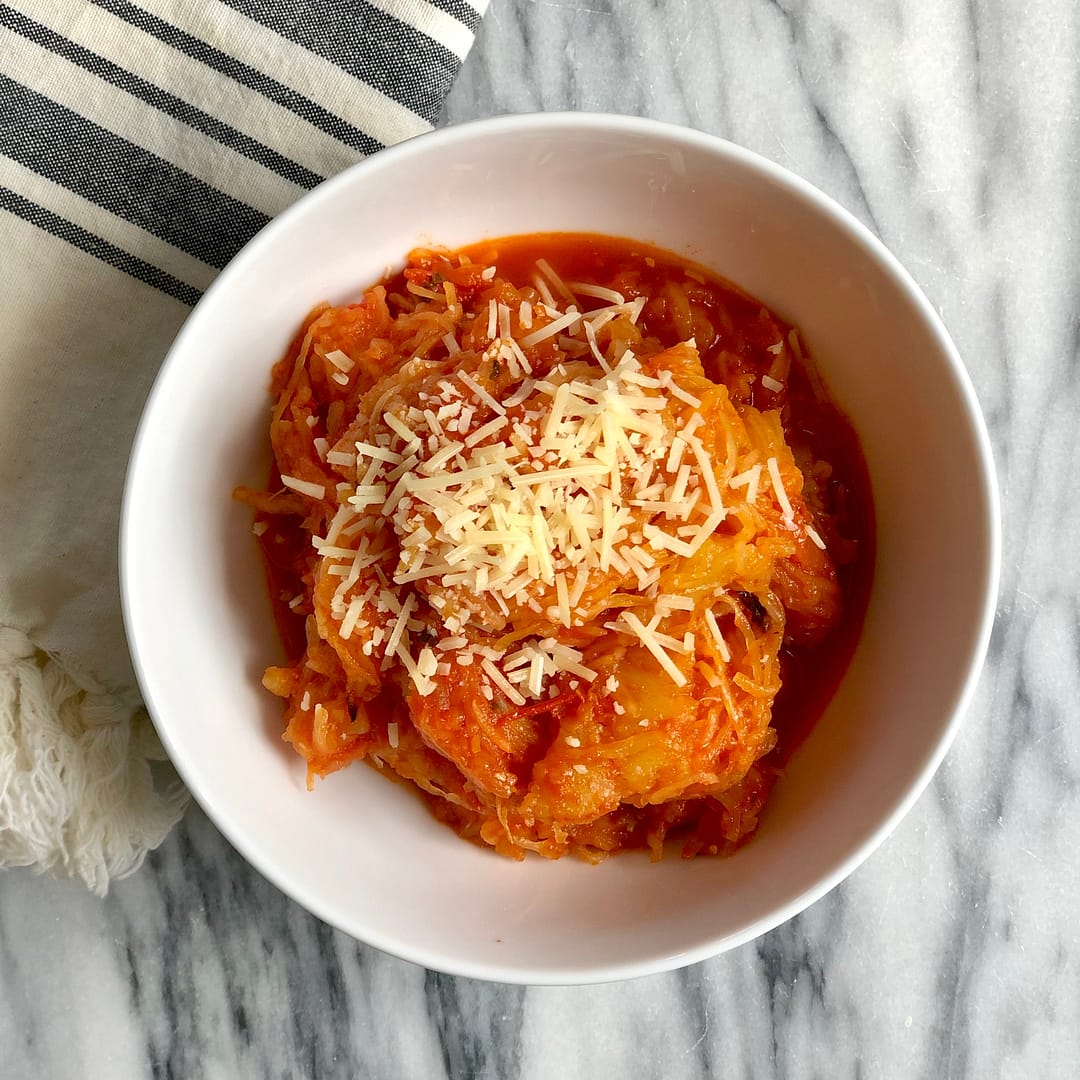 Bowl of spaghetti squash pasta with homemade sauce topped with parmesan cheese.