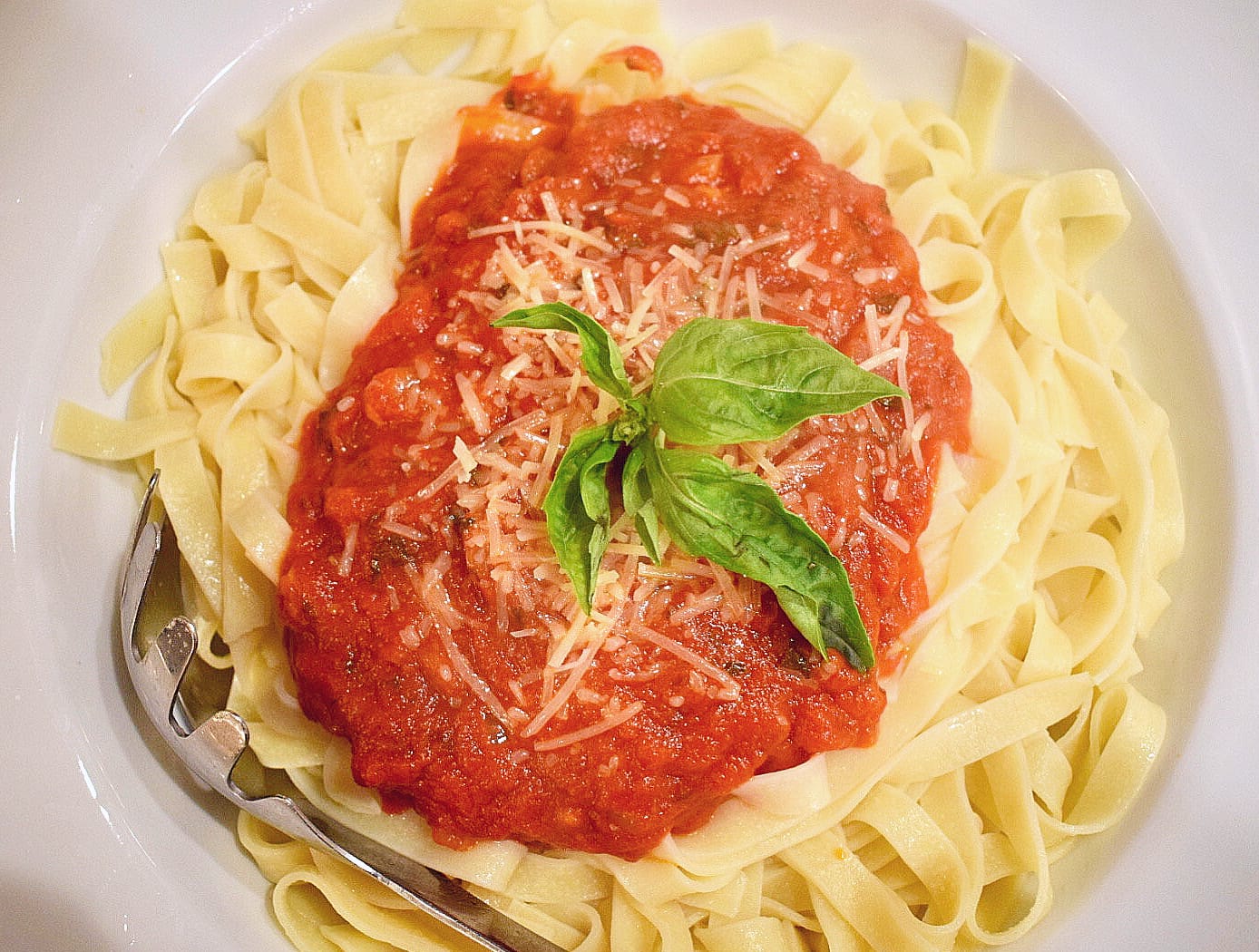 Easy homemade pasta sauce on gluten free pasta topped with basil and parmesan cheese