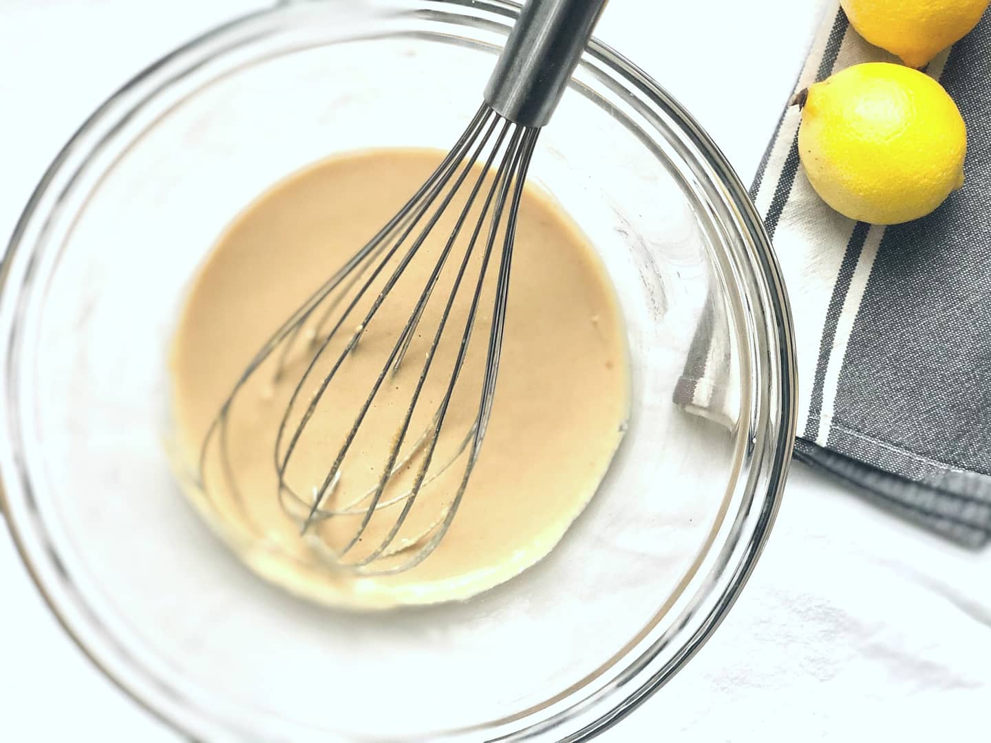 Miso tahini dressing & macro plate sauce with lemons in background..