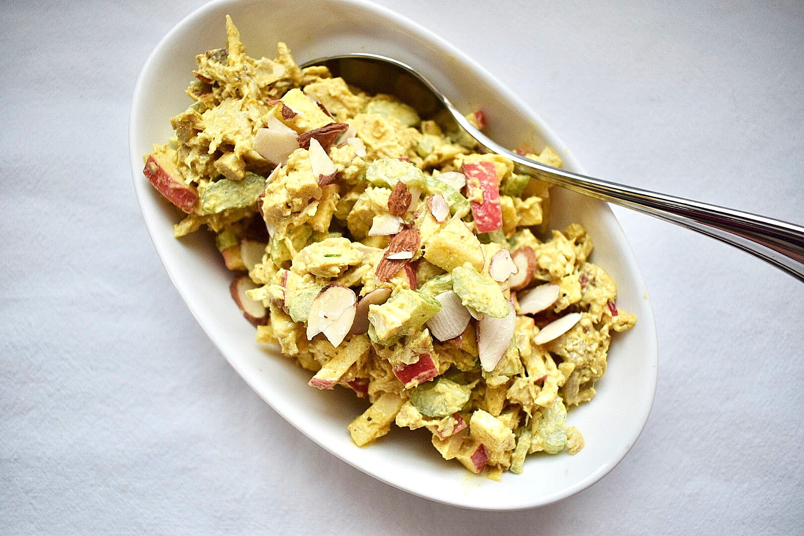 Curry chicken salad in white bowl on white background