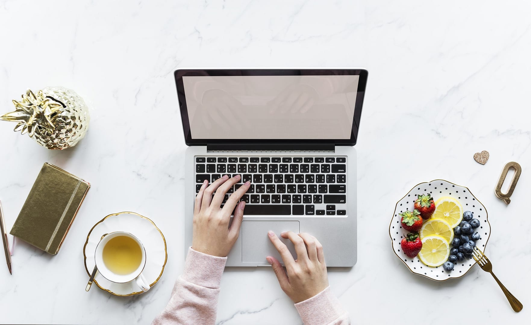 Woman at desk with laptop, tea and fruit